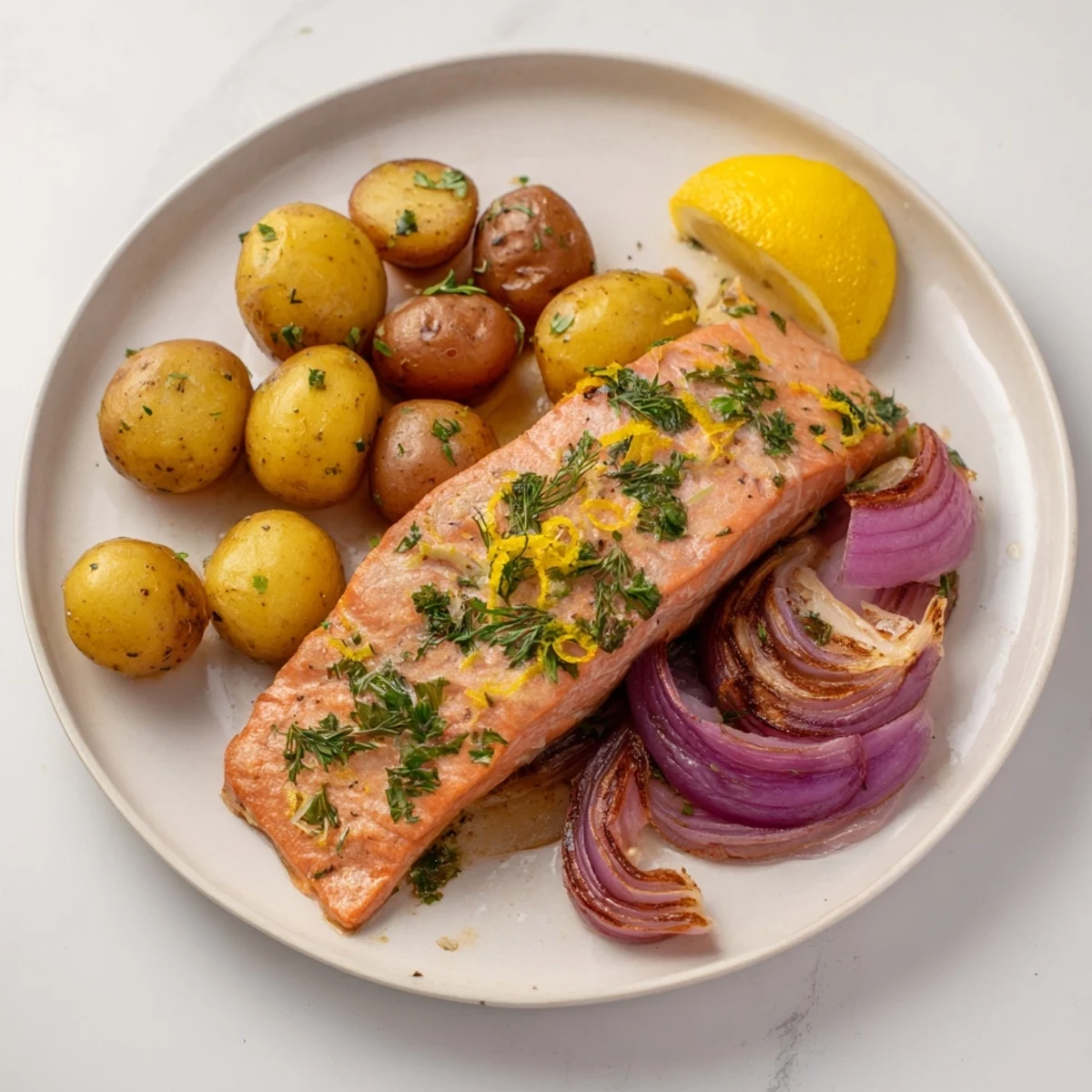 This sheet pan Lemon Herb Salmon & Potato recipe displays flaky salmon alongside golden, crispy potatoes.