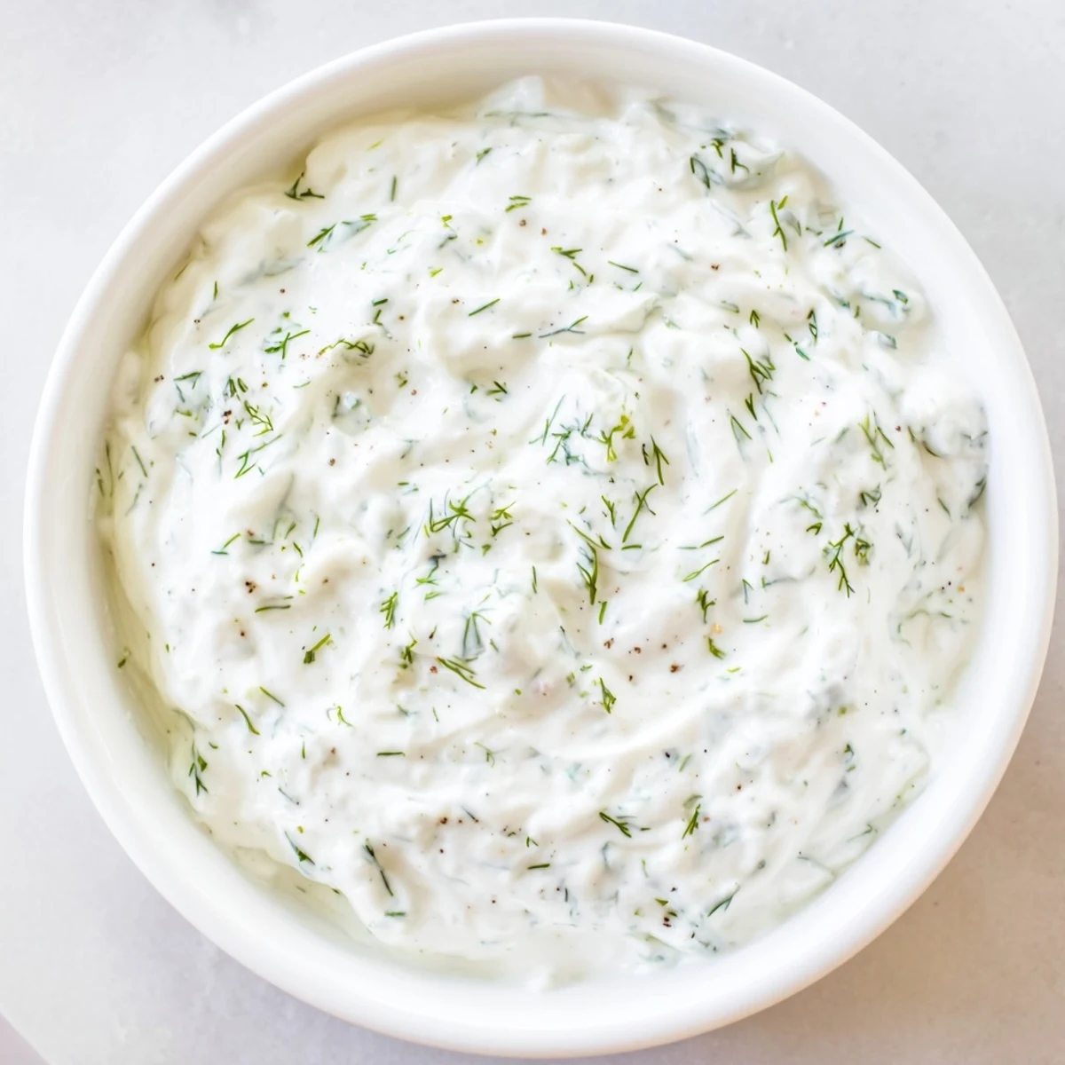 Cool, creamy Greek Yogurt Ranch Dip alongside colorful, fresh vegetables on a white plate.