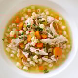 Golden broth swirling with ditalini in a bowl of Chicken and Ditalini Flu Fighter Soup.