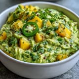 Creamy Cinco de Mayo guacamole with juicy mango and spicy jalapeño, perfect for dipping with tortilla chips.