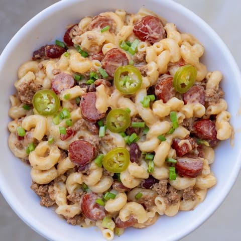 A close-up of creamy, cheesy Chili Cheese Dog Mac & Cheese, with chili visible beneath the golden crust.