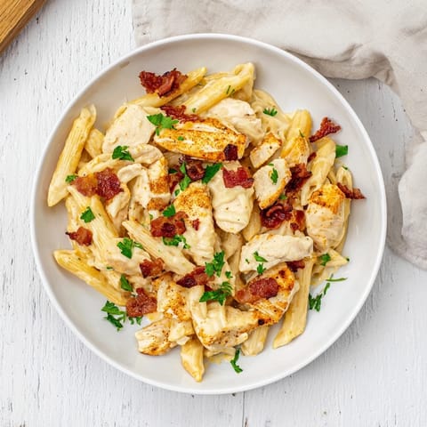 A close-up of Ranch Chicken & Bacon Penne, showing tender chicken and a rich, creamy cheese sauce coating the penne.