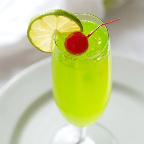 Sweet and bubbly Quick Grinch Mimosa Mocktail, a festive, non-alcoholic holiday drink creation.