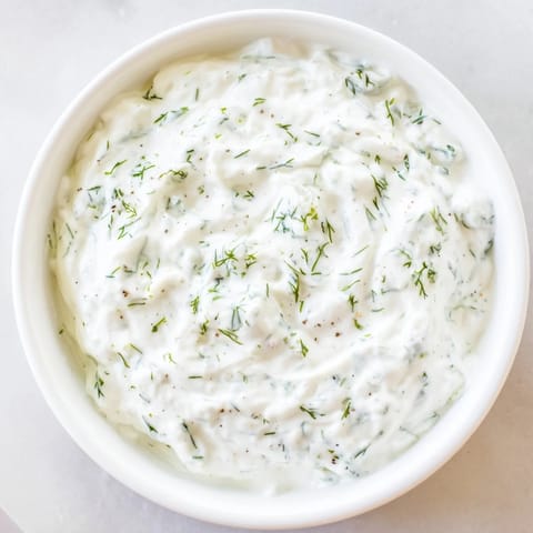 Cool, creamy Greek Yogurt Ranch Dip alongside colorful, fresh vegetables on a white plate.