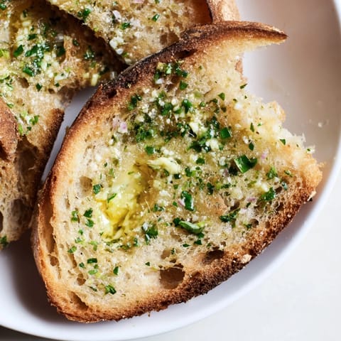 Slices of Herb Butter Toast sit beside a glass of crisp white wine, perfect for easy appetizer entertaining.