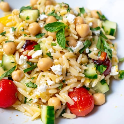 A vibrant bowl of Lemony Chickpea Orzo Salad, tossed with herbs and a zesty lemon vinaigrette.  
