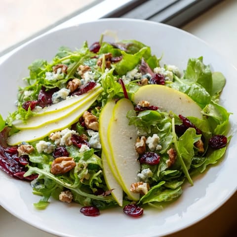 Fresh, crisp salad greens topped with juicy pear slices, crumbled Gorgonzola, and toasted walnuts, drizzled with honey-balsamic vinaigrette.
