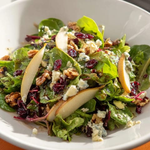Pear Gorgonzola Salad garnished with crumbled blue cheese and walnuts, served as a refreshing vegetarian starter or light lunch.