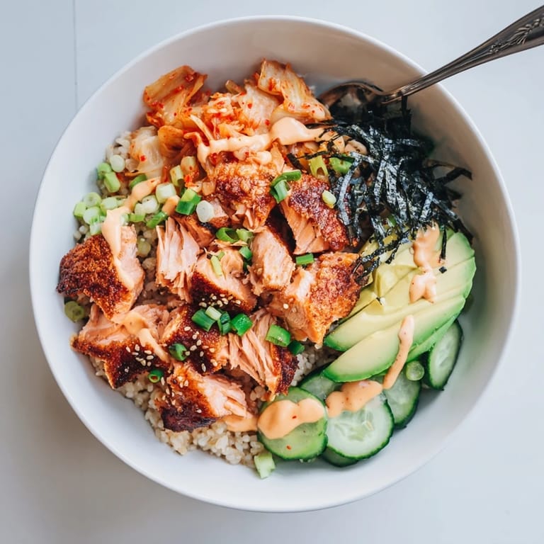 Flavor-packed crispy salmon rice bowl with tangy kimchi and fresh cucumber slices.
