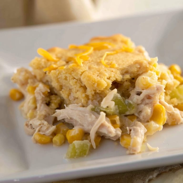 A close-up of bubbly Southern Cornbread Chicken Casserole with steam rising from the savory filling.