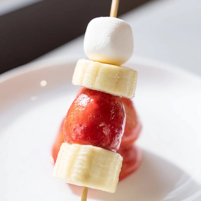 Vibrant, festive Strawberry Banana Santa Sticks feature banana rounds beneath marshmallow "pom-poms" and a strawberry hat.