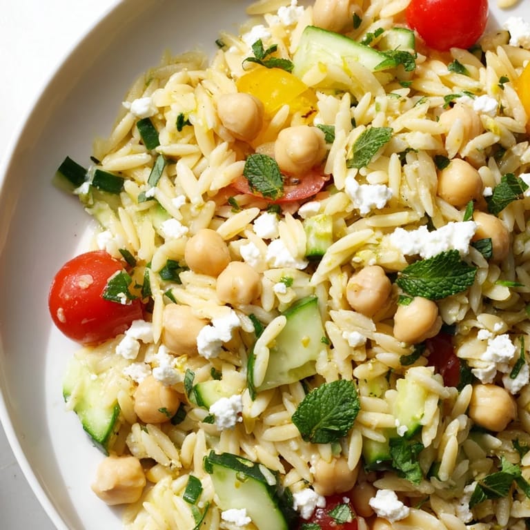 Chilled Lemony Chickpea Orzo Salad featuring chickpeas, feta crumbles, and mint for a refreshing picnic side.